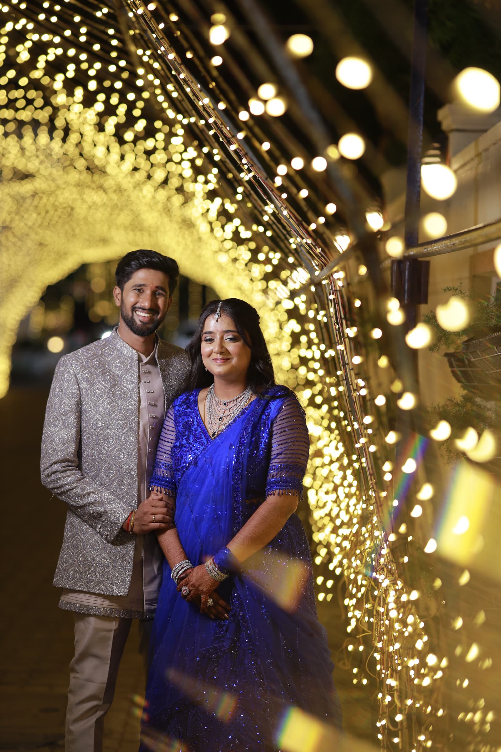 Couple standing beneath warm fairy lights