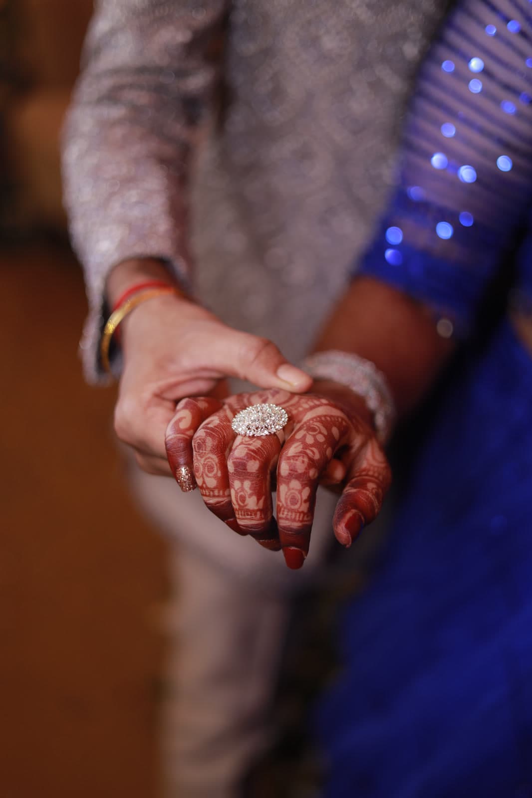 Close-up of hands with henna patterns and a solitaire diamond ring