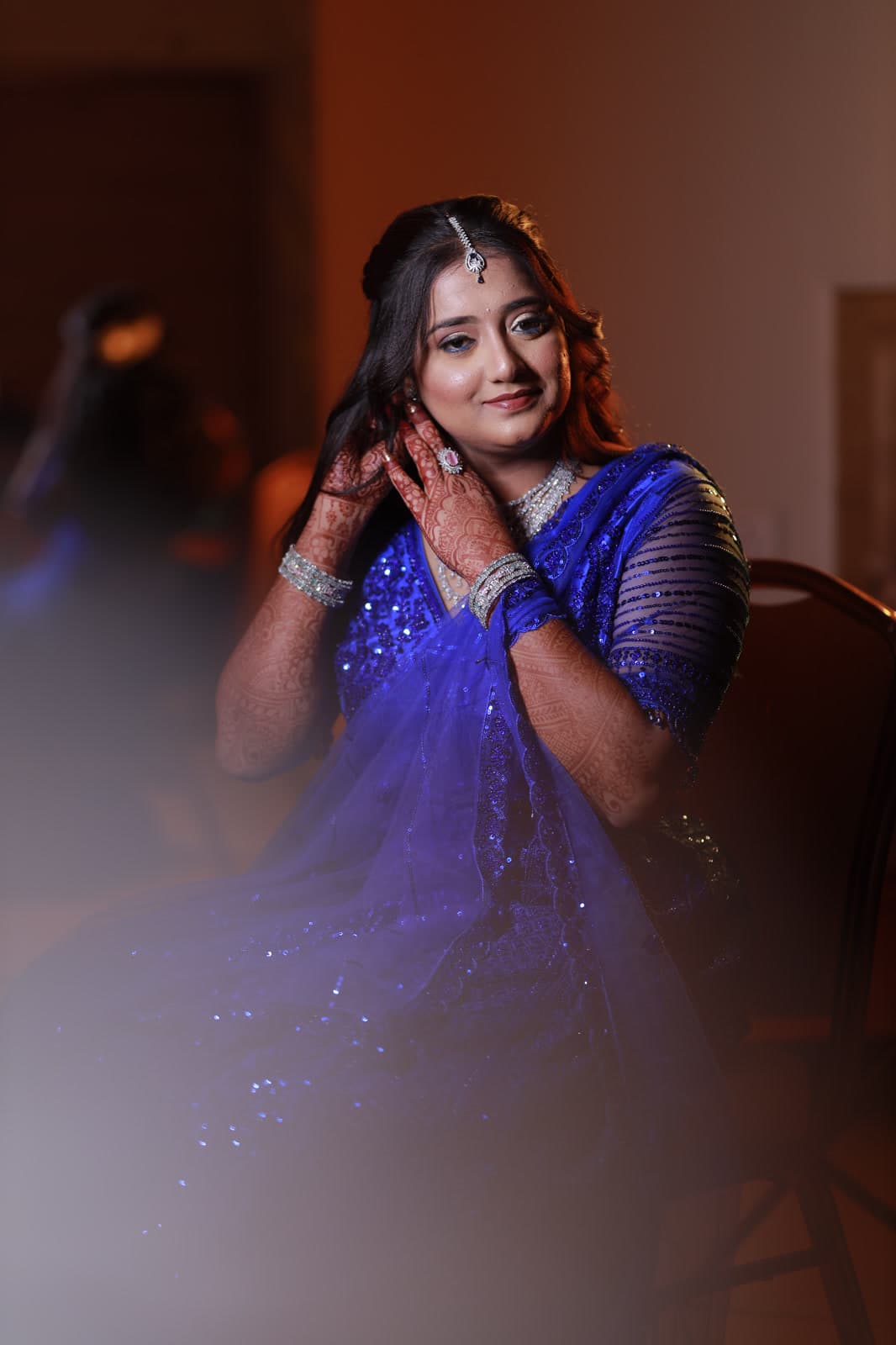 Woman in royal blue saree adjusting a diamond earring